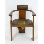 An Arts and Crafts oak desk chair with an upholstered back rest and seat with studded detailing.