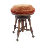 A late 19thC / early 20thC piano stool with an adjustable upholstered top above four ring turned