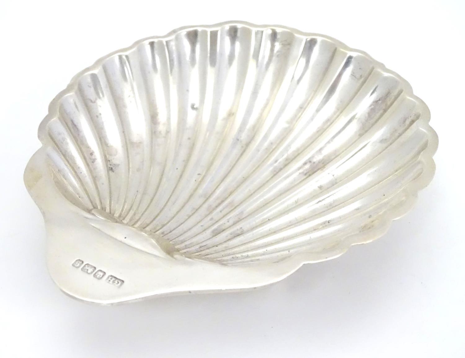 A silver scallop-shaped dish raised on three bun feet. Hallmarked Sheffield 1910 maker Harrison