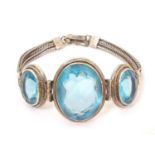 A white metal bracelet set with three large graduated aquamarine coloured stones. Please Note - we