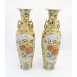 A pair of large Oriental vases with twin handles of stylised form decorated with flowers and foliage