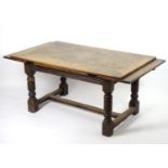 An early 20thC oak dining table, with a rectangular table top above two draw leaves, the table