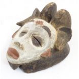 Ethnographic / Native / Tribal: A carved African mask with polychrome decoration. Approx. 13" long