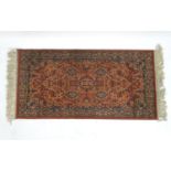 Carpet / Rug : An orange red ground rug with central medallions and floral detail. Approx 61" x