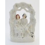A Staffordshire pottery flat back figural group depicting a seated young couple under a garden arch.