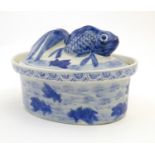 A Chinese blue and white dish and cover of oval form, the lid surmounted by a fish in relief, the