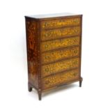 An early 20thC mahogany and satinwood inlaid chest of drawers with a shaped top above six long