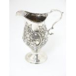 A Victorian silver cream jug with embossed floral and C scroll decoration hallmarked London 1898,