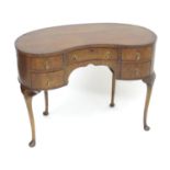 An early 20thC kidney shaped mahogany dressing table, with five short drawers with drop style