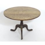 A mid / late 18thC oak tilt top tripod table with a circular top above a turned pedestal base and