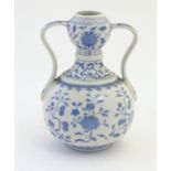 An Oriental blue and white double gourd vase with twin handles decorated with scrolling floral and