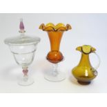 Three 19thC / 20thC items of glassware comprising an amber glass jug and vase and a cup and cover