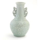 A Chinese celadon green baluster vase with twin handles and stylised foliate design. Approx. 6 1/