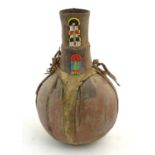 Ethnographic / Native / Tribal: An African gourd bottle / container with beaded detail. Approx. 15