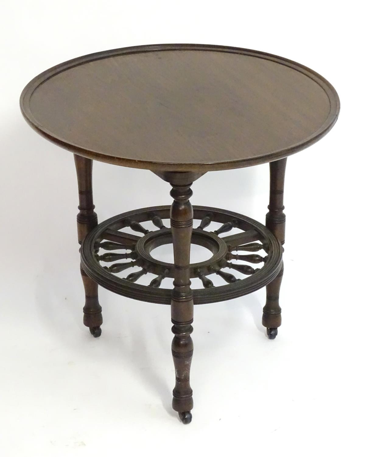 A late 19thC mahogany occasional table with a lazy Susan top and rounded under tier with turned