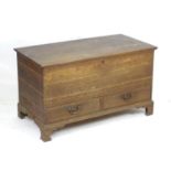A Georgian oak mule chest with a moulded lid above two short drawers and raised on shaped bracket