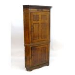 A mid / late 18thC oak double corner cupboard with a moulded cornice above a satinwood inlaid frieze