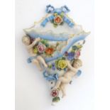 A German porcelain wall pocket decorated with two cherubs / putti and flowers in relief. Marked