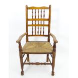 An early 20thC rush seated spindle back open armchair Please Note - we do not make reference to