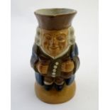 A Royal Doulton Lambeth stoneware Toby character jug, The Standing Man, wearing a brown hat and