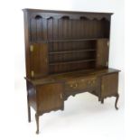 An early 20thC oak dresser with a moulded cornice above a shaped frieze and plate rack flanked by