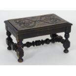 An early 20thC footstool with a carved top above four turned legs united by a H-stretcher. 13"