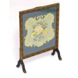 A 20thC fire screen with a moulded surround above a glazed needlework centre. 22" wide x 28" high.