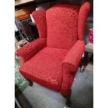 A red upholstered wingback armchair on ball and claw feet Please Note - we do not make reference