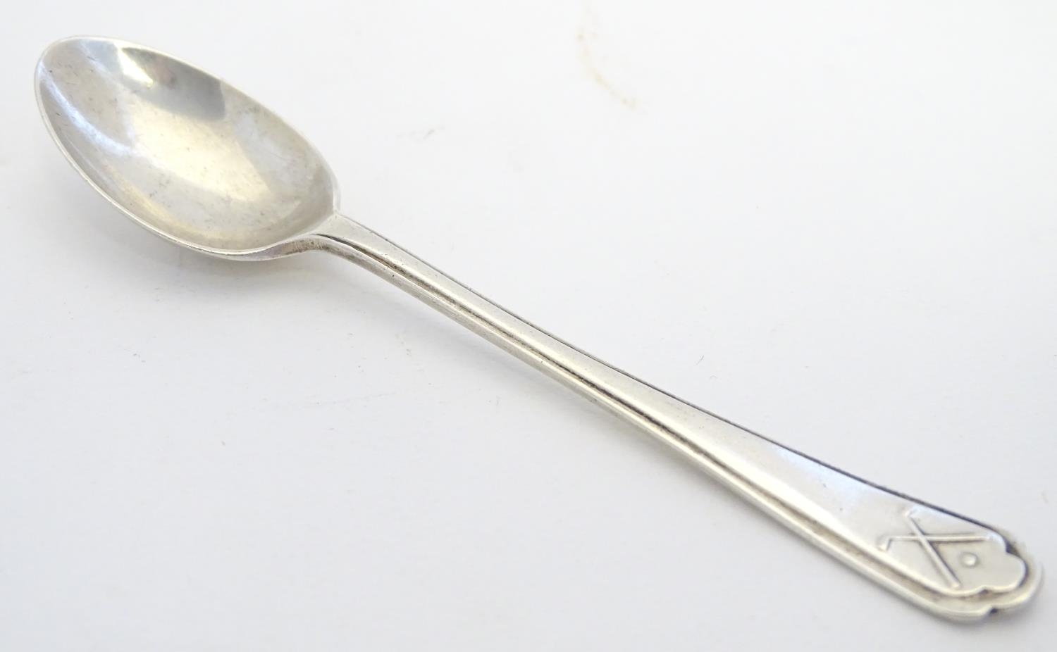 A silver teaspoon with crossed gold club and ball decoration to handle. Hallmarked Chester 1933