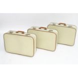 A mid 20thC set of three travelling suitcases by Cheney, London, in white with tan trim, each with