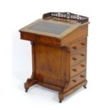 A late 19thC walnut davenport with a pierced carved gallery above a writing slope and an inlaid