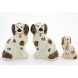 A pair of Staffordshire pottery seated spaniels, together with another smaller example. Largest