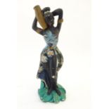 A 20thC model of an African lady in an floral dress carrying a water vase. Approx. 17" high Please