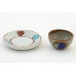 A small saucer with naive hand painted decoration, together with a small tea bowl decorated with the