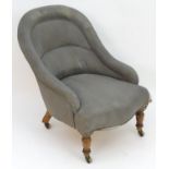 A small early 20thC upholstered tub armchair with walnut legs and brass castors. Stamped L.20264