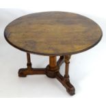 A mid / late 19thC oak centre table with a circular top above four turned supports and rosette