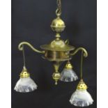 An Arts & Crafts brass pendant ceiling light, with three scrolling branches suspending Holophane