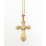 A 14ct gold pendant of cross form set with central white stone, 1 1/2" long. With yellow metal chain