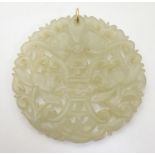 An Oriental carved pale jade coloured pendant of circular form. Approx. 2 1/4" diameter Please