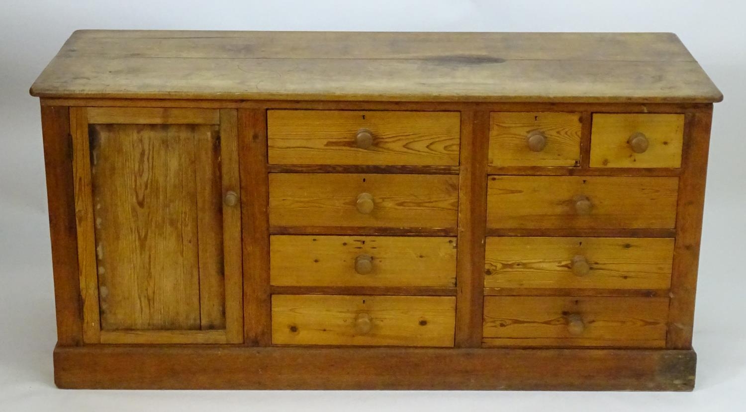 A late 19thC pine dresser base with a moulded rectangular top above a single cupboard, seven short