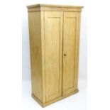 An early 20thC pine wardrobe with a moulded cornice above two panelled doors. 38" wide x 18" deep