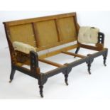 A late 19thC Aesthetic movement sofa with an ebonised chamfered frame with pierced arm supports,