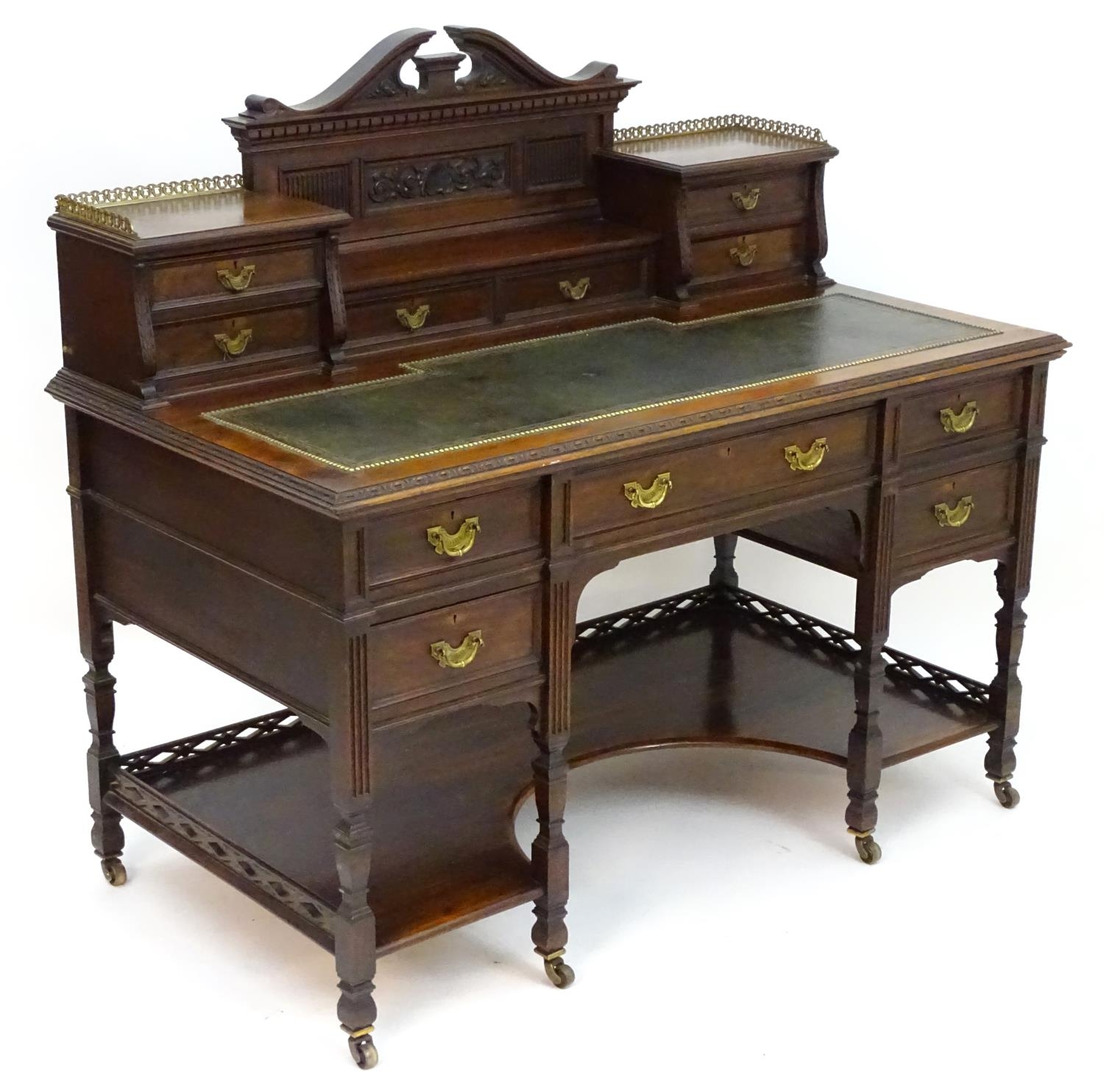 A late 19thC / early 20thC walnut Shoolbred desk with a carved back stand and a pierced brass