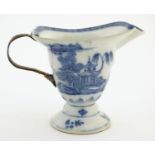 A helmet jug with blue and white decoration with a stylised landscape scene with pagodas,