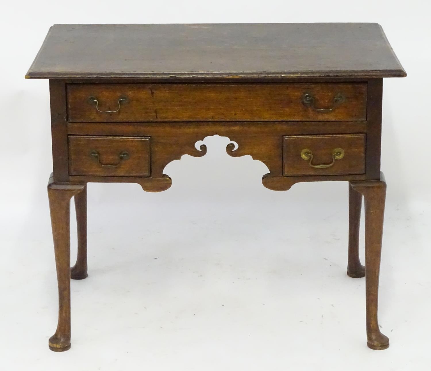 A mid 18thc oak lowboy with a moulded rectangular top above a single long and two short drawers with