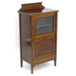 An Edwardian mahogany music cabinet with an upstand above a crossbanded structure and a glazed