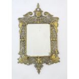A 19thC bevelled glass mirror with a brass surround with pierced scrolling foliate, mask and