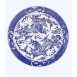 A Chinese blue and white plate decorated with dragons with flaming pearls amongst stylised clouds.