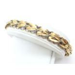 An 18ct gold bracelet decorated with stylised honesty leaf detail, marked 18K approx 7" long