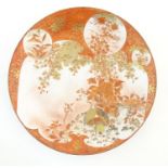 A Japanese Kutani charger with crane birds in a landscape with blossom, foliage and gilt highlights.